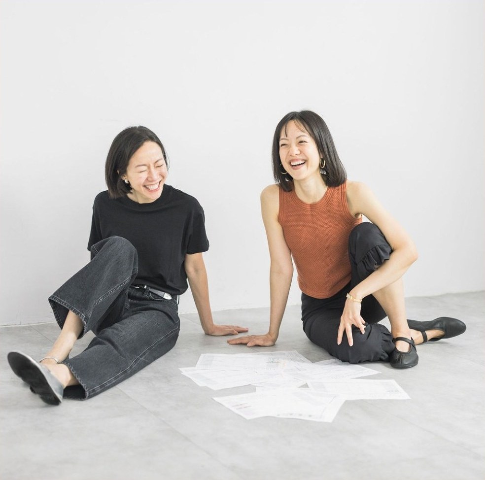 Annie 和 Terrie 坐在地上整理講義、開懷大笑